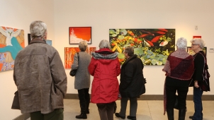 People standing and viewing paintings in an art gallery People standing and viewing paintings in an art gallery